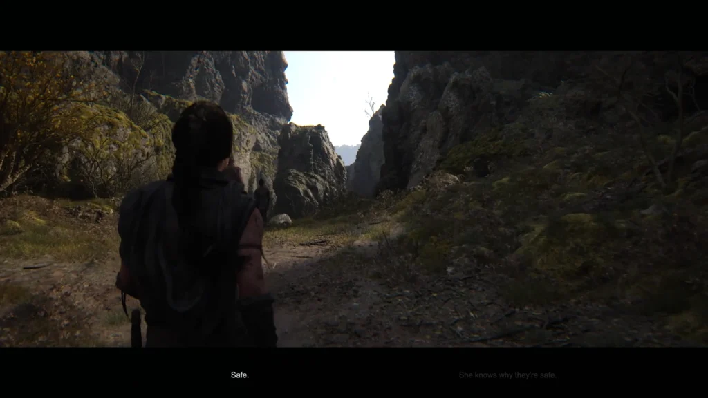 Женщина идет по тропе в горном ущелье