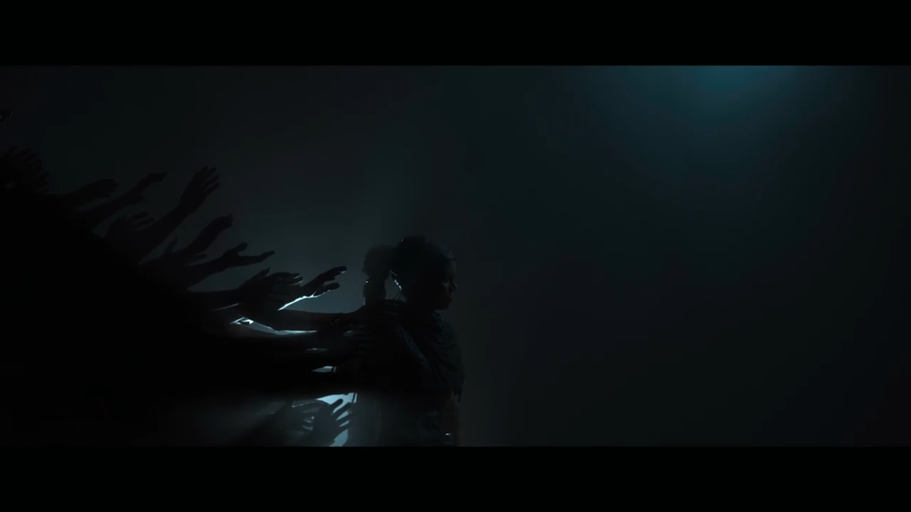 Силуэт женщины стоит в темноте, тени рук тянутся