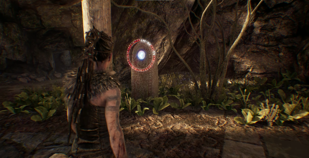 Сенуа из Hellblade смотрит на рунический камень в пещере