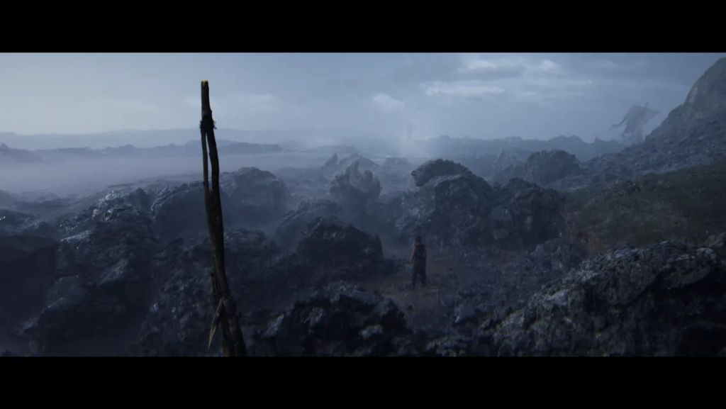 Человек стоит среди серых скал в тумане