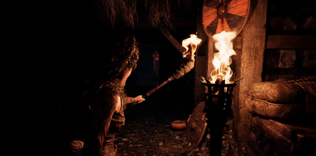 Сенуа из Hellblade держит факел в хижине