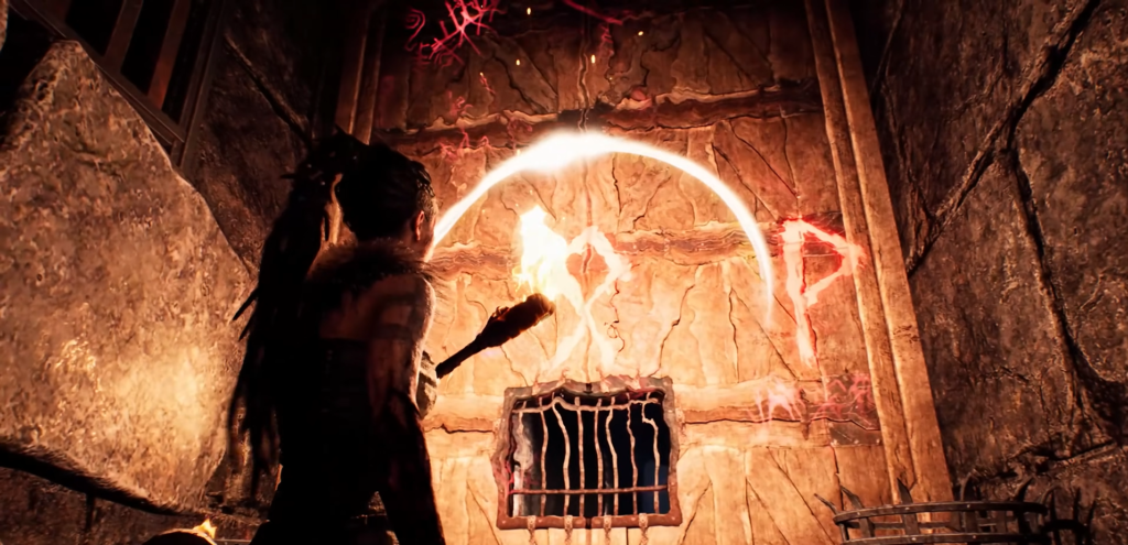 Сенуа держит факел у рунической стены в пещере