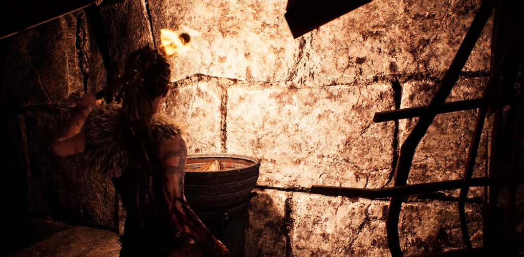 Сенуа из Hellblade держит факел у каменной стены
