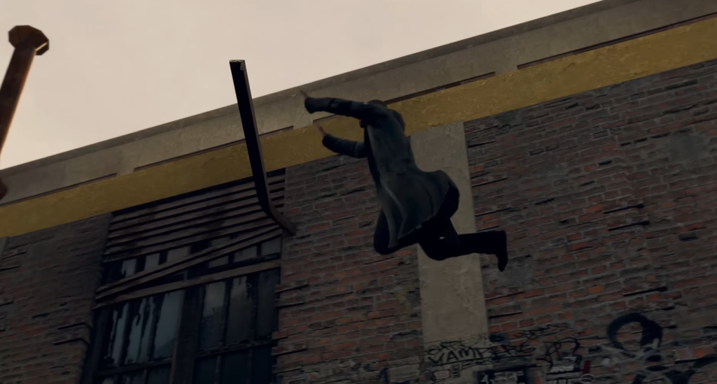 Человек в чёрном пальто прыгает у кирпичной стены