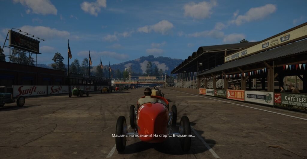 Красный гоночный болид стоит на стартовой решетке трассы