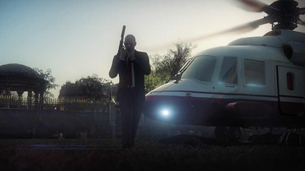 Агент 47 из Hitman стоит у вертолёта на лужайке